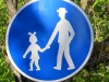 In Tschechien wird ein Fussweg mit einem Schild markiert, auf welchem ein Mädchen mit Schleifchen im Haar einen Mann hinter sich herzieht